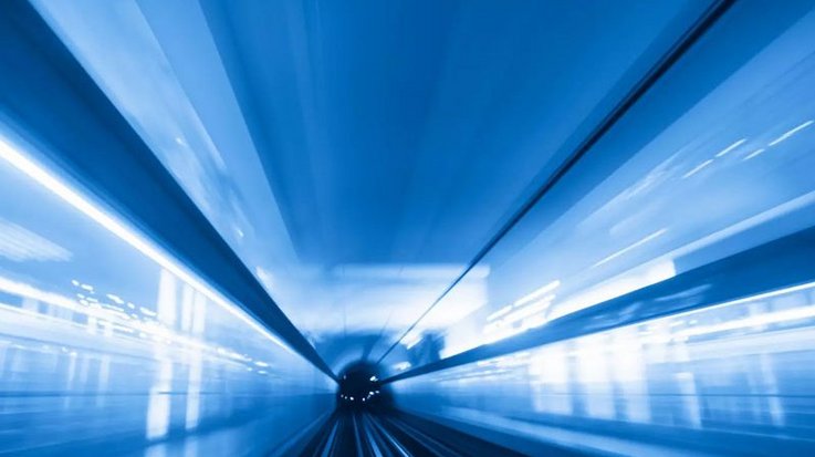 Blick in einen mit blauem Licht beleuchteten Tunnel mit Gleisen