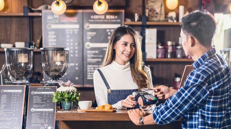 Ein Mann bezahlt kontaktlos mit einer Kreditkarte in einem Café