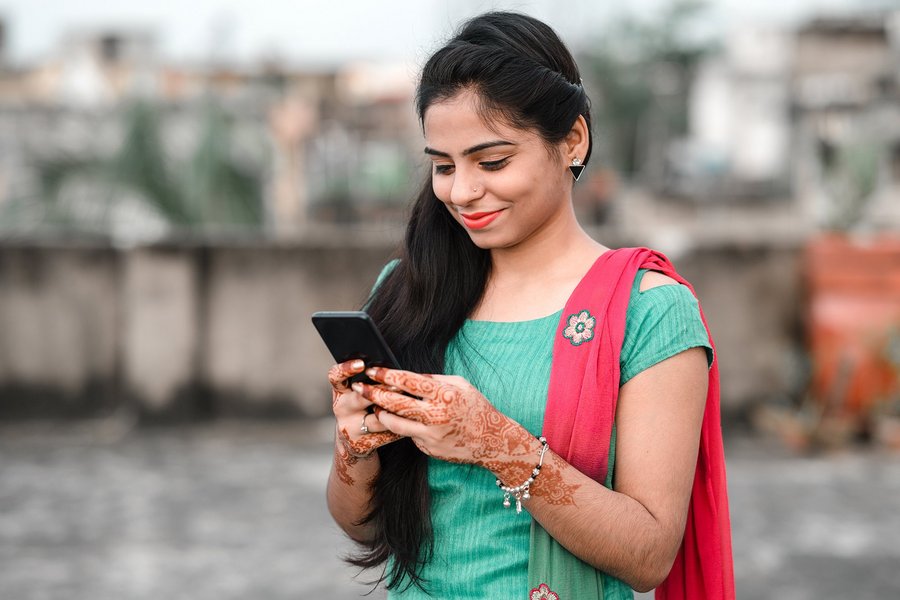 A Bangladeshi woman smiling at her smartphone