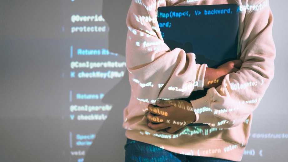 A source code is projected onto a woman and the wall behind her.