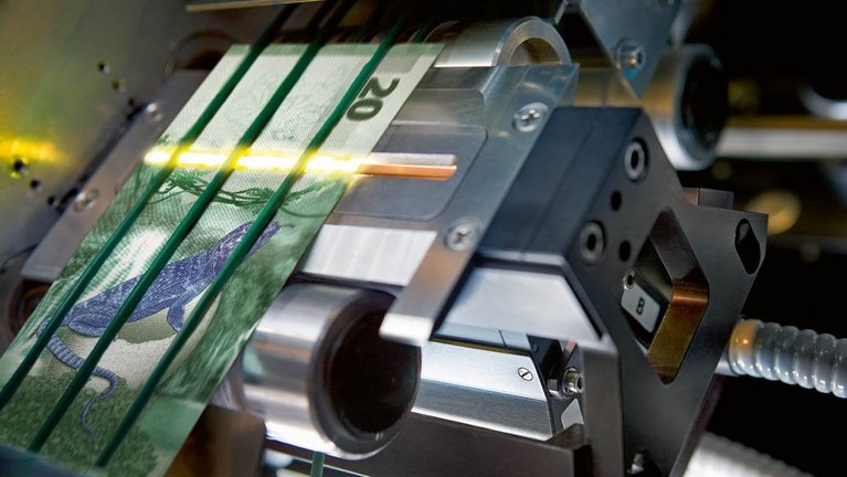 Nahaufname einer Banknotenbearbeitungsmaschine mit Ultraschallsensoren und einer Musternote