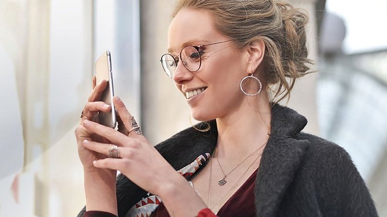 Smiling woman operates her smartphone