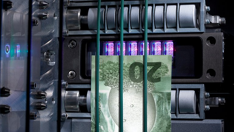 Blick in das innere einer Maschine, durch die eine Banknote läuft
