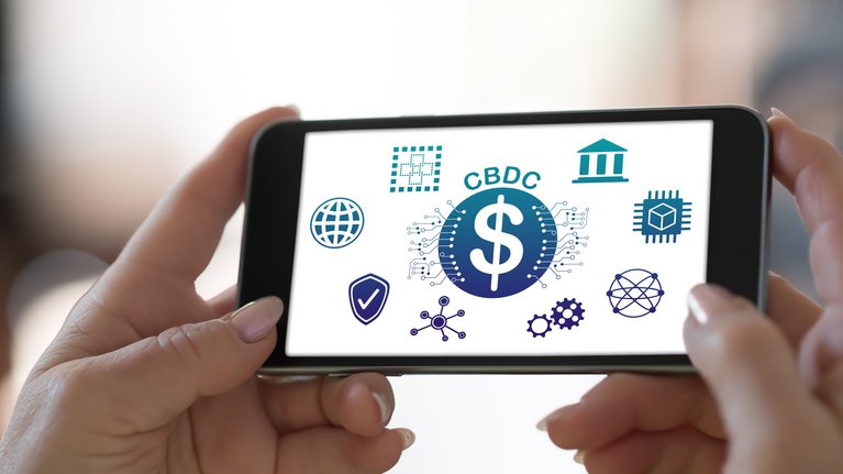 Someone is holding a smartphone with 'CBDC' written on the screen, surrounded by various symbols