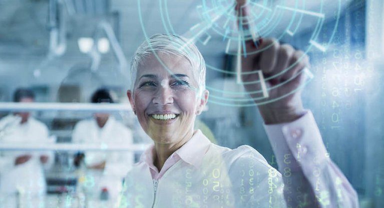 Eine in weiß gekleidete Frau in einem Labor drückt mit dem Finger auf eine computersimulierte Anzeige
