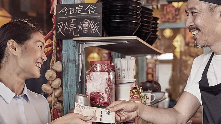 A woman pays with a banknote in an Asian restaurant