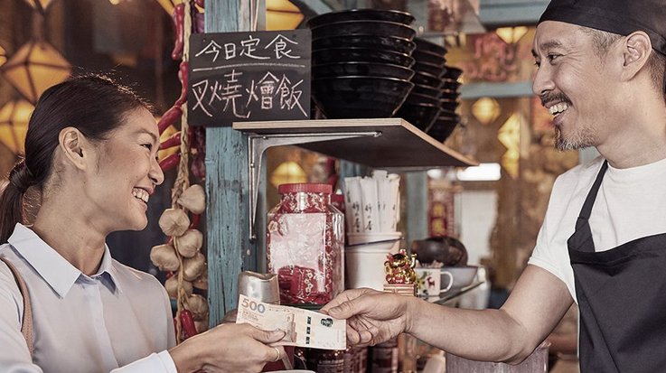 A woman pays with a banknote in an Asian restaurant