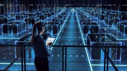 Woman using a tablet and standing in front of server farm made of digital structures