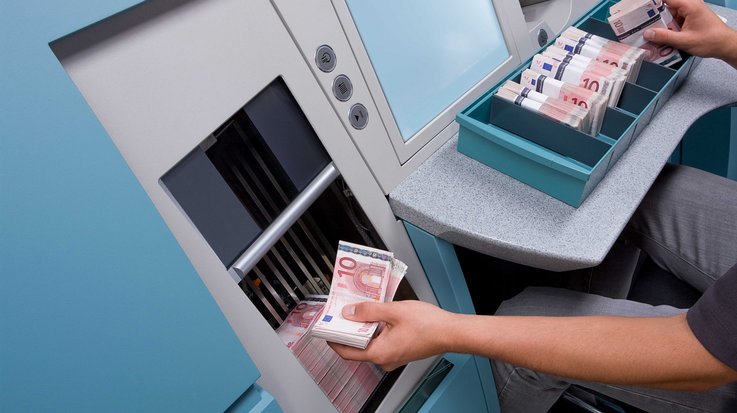 Ein Mitarbeiter entnimmt sortierte Eurobanknoten aus dem Banknotenbearbeitungssystem BPS® M7