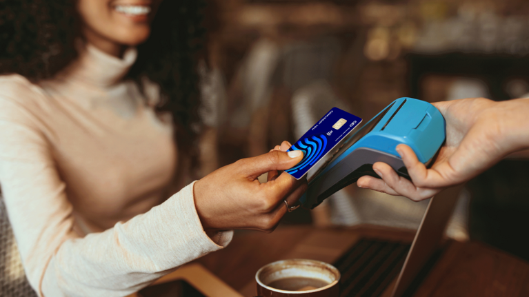 Foto einer Frau, die ihre Bezahlkarte an ein Bezahlgerät hält