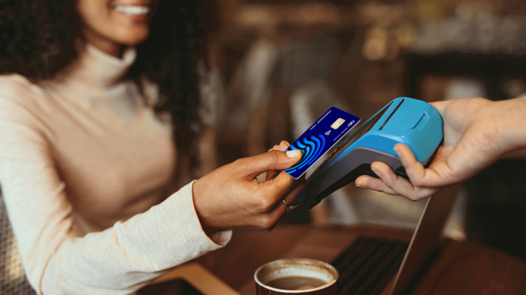Photo of a woman holding her payment card to a payment device