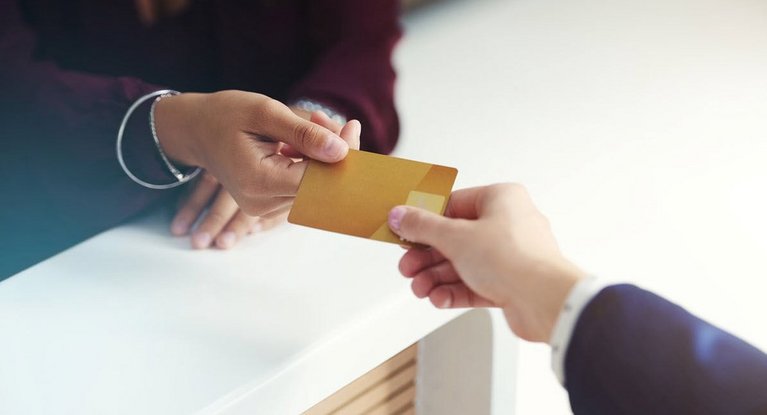One person presents another with a gold credit card