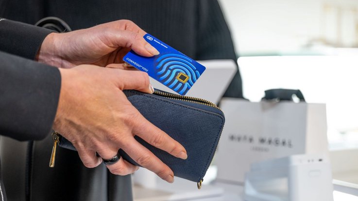 Eine Frau in Business-Kleidung nimmt eine G+D Convego YOU Kreditkarte aus ihrer Geldbörse