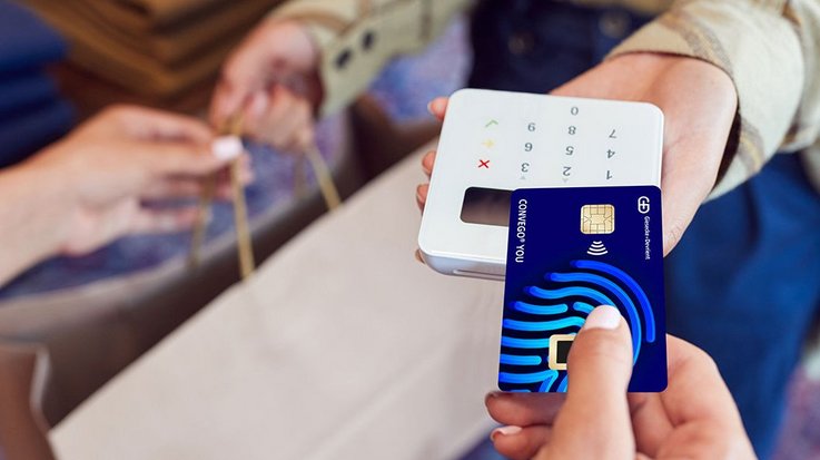 Eine Kundin bezahlt ihren Einkauf in einem Bekleidungsgeschäft kontaktlos mit der Convego You Kreditkarte