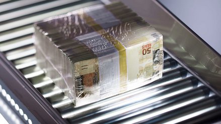Ein Stapel verpackter Banknoten auf einem Förderband