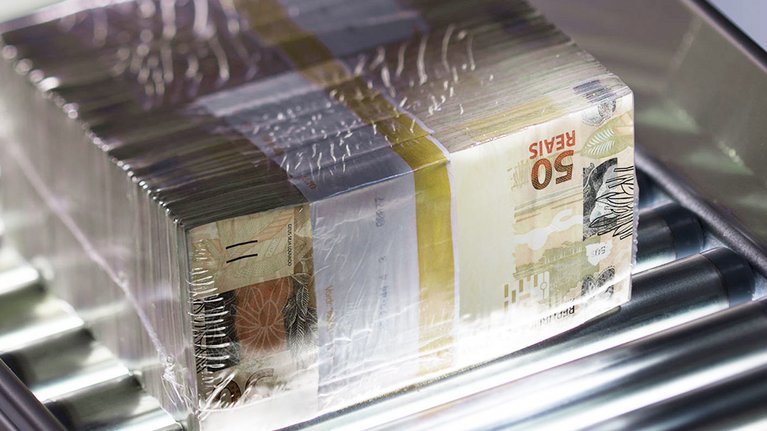 Ein Stapel verpackter Banknoten auf einem Förderband