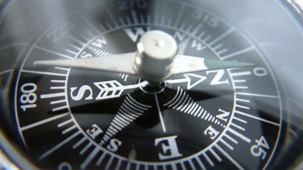 Close up of compass with black background and white lettering