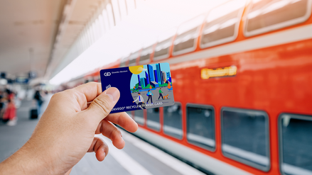 photo of holding a transit card with a train in the background