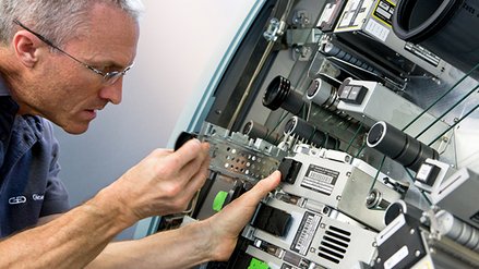 A service technician handles an opened banknote processing system from G+D