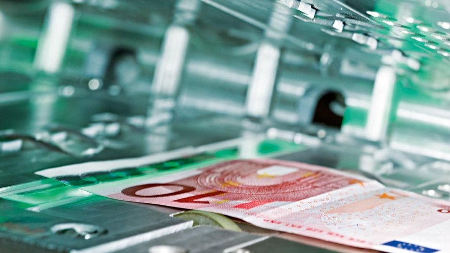Ein 10€-Schein läuft durch eine Geldzählmaschine