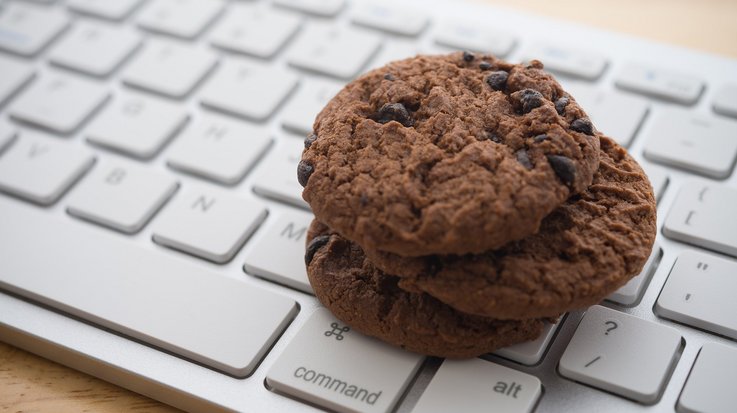 Two chocolate chip cookies lying on a computer keyboard