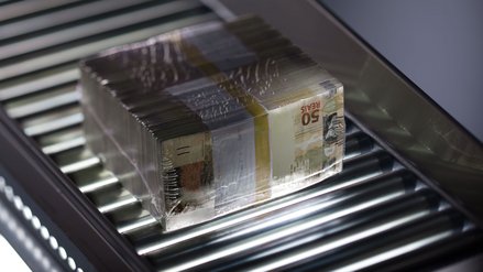 Ein Stapel Geldscheine kompakt mit Folie verpackt auf einem Förderband