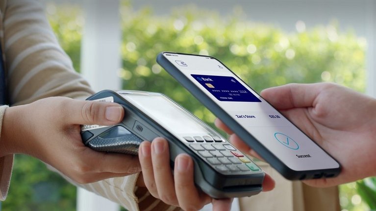 Eine Person bezahlt kontaktlos mit ihrem Smartphone, auf dem Screen erscheint die Abbildung einer Kreditkarte 