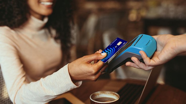 Eine Frau bezahlt in einem Café kontaktlos mit ihrer G+D Convego You Kreditkarte