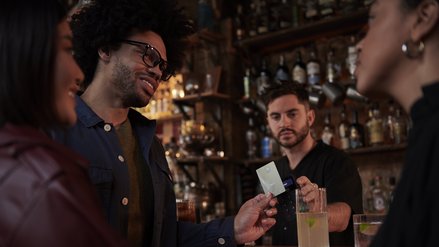 A young man pays at a bar with a metal credit card