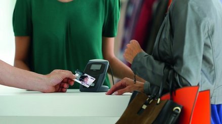 Eine Frau mit Einkaufstaschen bezahlt kontaktlos mit ihrer Kreditkarte