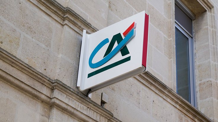 Logo von Credit Agricole auf einem Leuchtschild an einem Gebäude