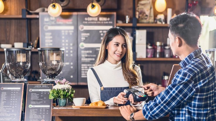 Ein Mann bezahlt kontaktlos mit einer Kreditkarte in einem Café
