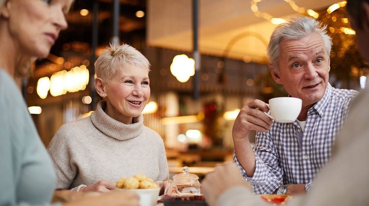 Vier ältere Menschen sitzen zusammen an einem Tisch und essen und trinken gemeinsam