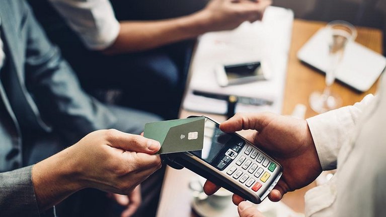 In Mann in Businesskleidung bezahlt kontaktlos mit seiner Kreditkarte in einem Restaurant