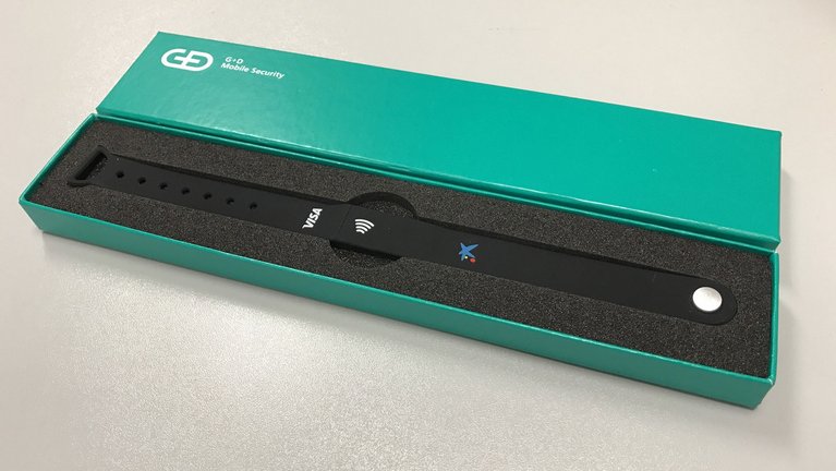 A black wristband from G+D in a box with a green lid