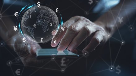 Ein Mann bedient ein Smartphone, darüber schwebt ein digitaler Globus und Finanzsymbole