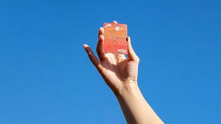 Person holding payment card against blue sky