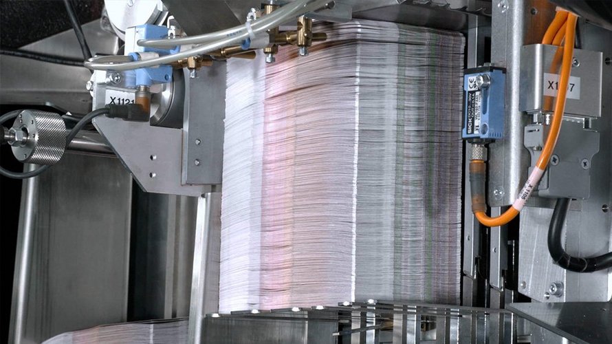 Many layers of colored paper are stacked in a machine