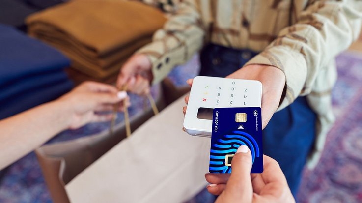 Eine Frau bezahlt ihren Einkauf in einem Modegeschäft kontaktlos per Kreditkarte