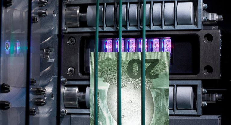 Blick in das innere einer Maschine, durch die eine Banknote läuft