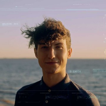 A man on a sunny beach looks into the camera with biometric scan data intricately displayed on his face and the backdrop.
