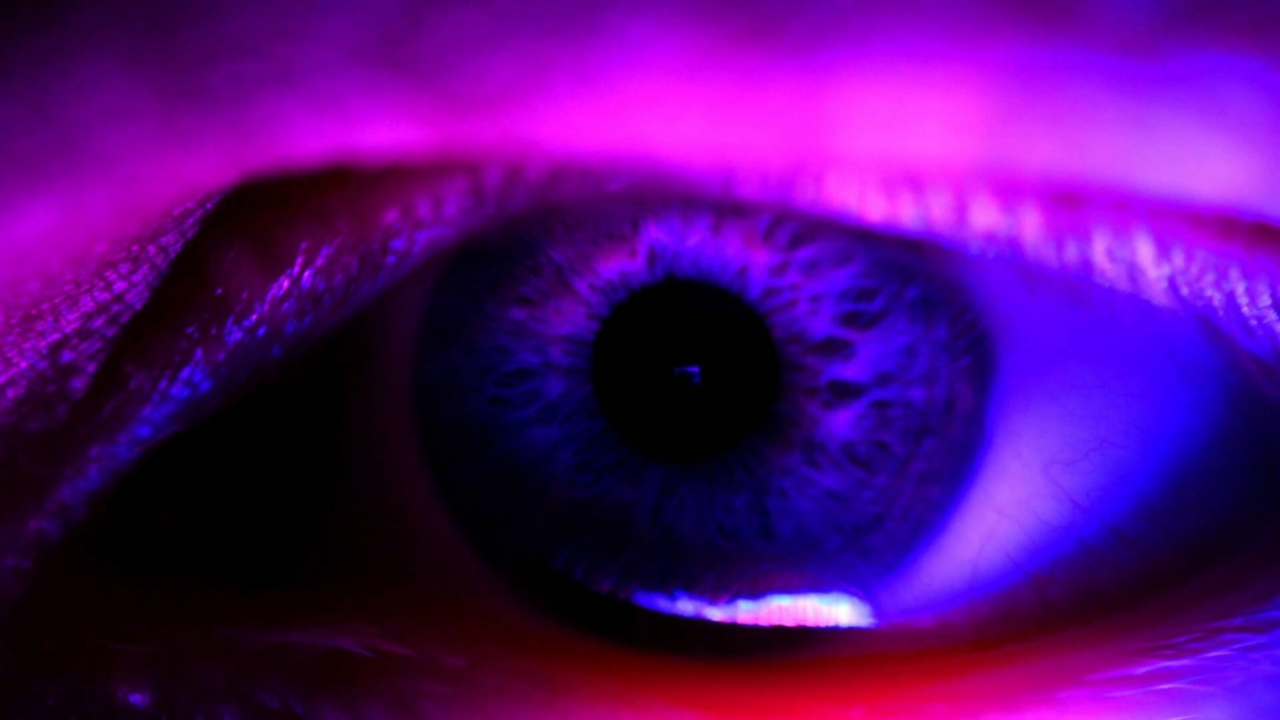 Close up of eye glowing in black light
