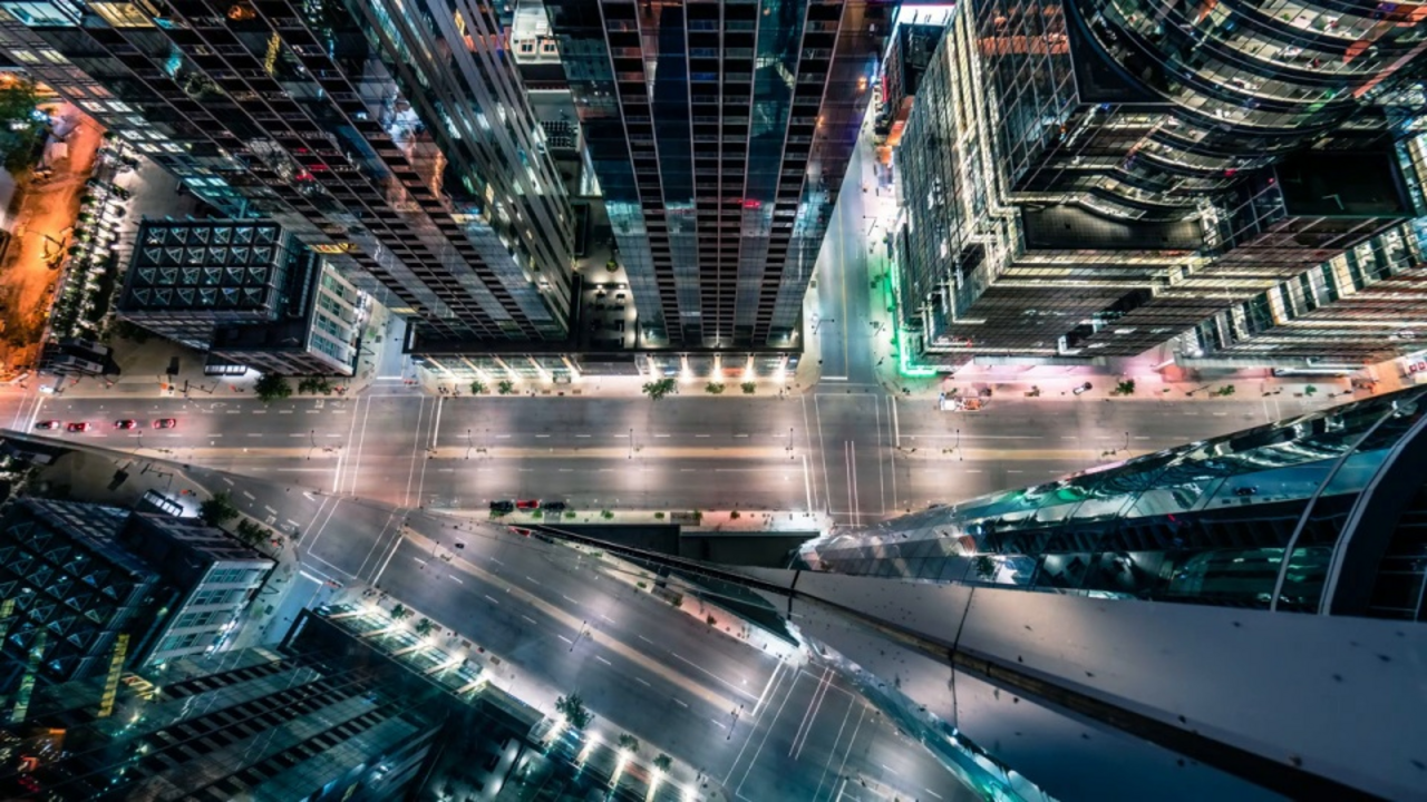 Vogelperspektive einer beleuchteten Großstadt bei Nacht mit einer mehrspurigen Straße