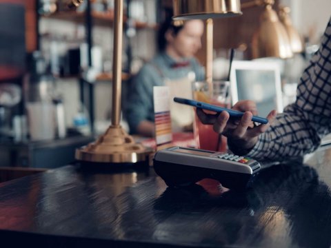 Ein Mann bezahlt an einer Bar kontaktlos mit seinem Smartphone