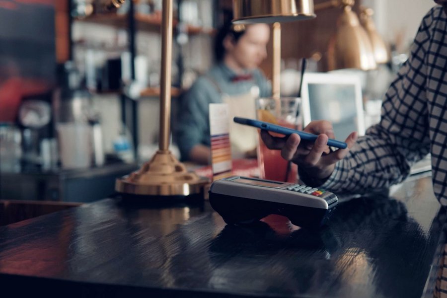 Ein Mann bezahlt an einer Bar kontaktlos mit seinem Smartphone