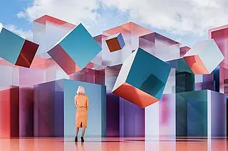 Eine Frau im orangefarbenen Kleid betrachtet schwebende, geometrische, bunte Würfel.