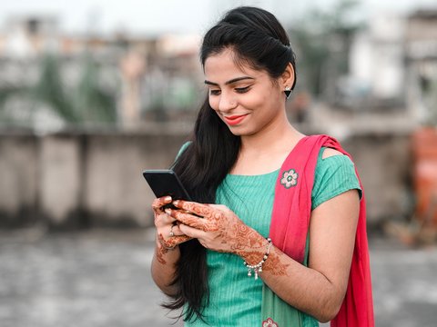 Eine lächelnde Frau blickt in ihr Smartphone