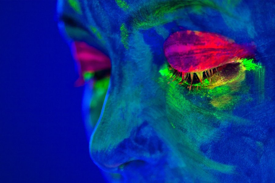 Portrait painted with fluorescent makeup that glows under the ultraviolet light. UV light is one of the security features for securing documents.
