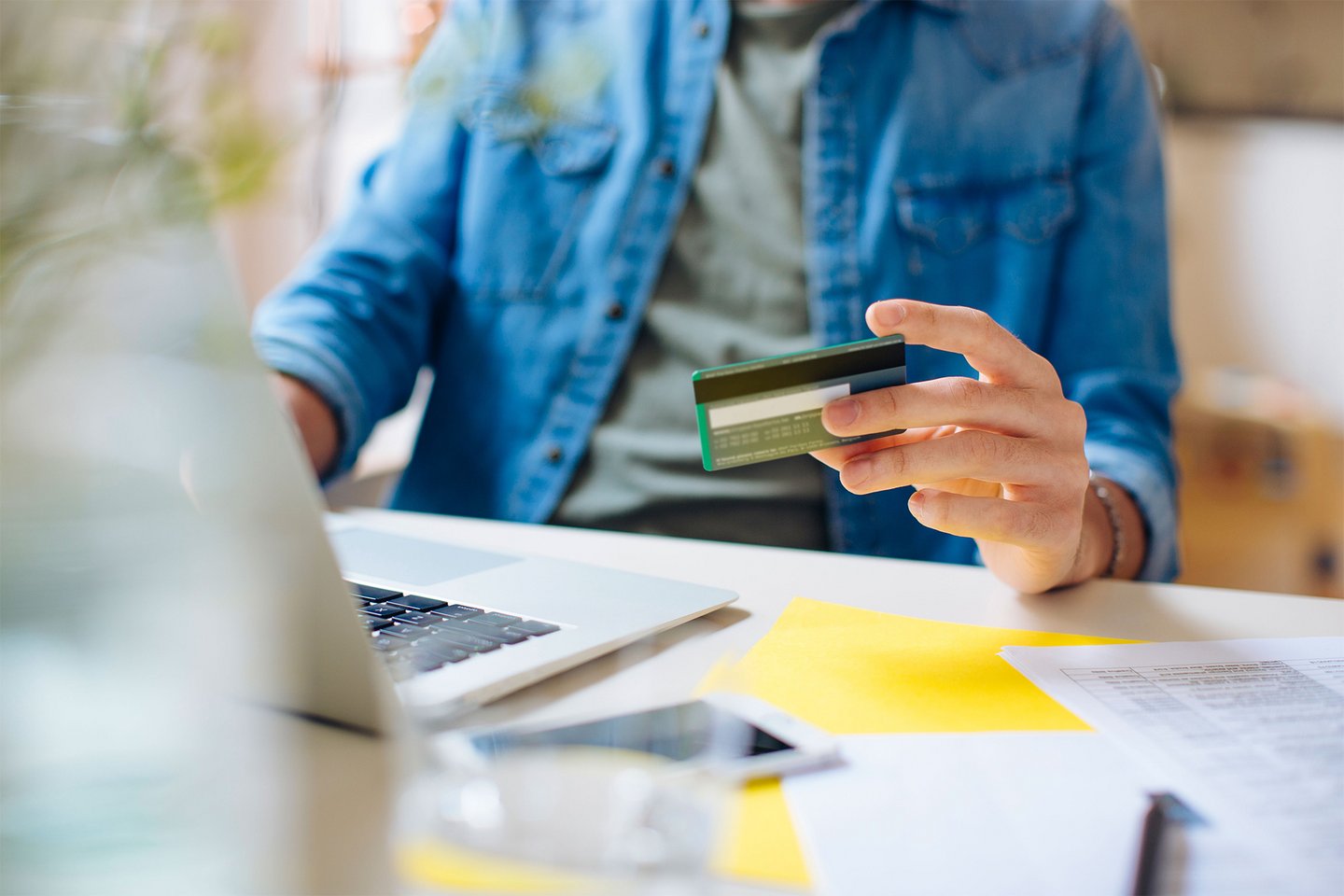 Nahaufnahme eines Mannes, der mit seiner Kreditkarte etwas online bezahlt
