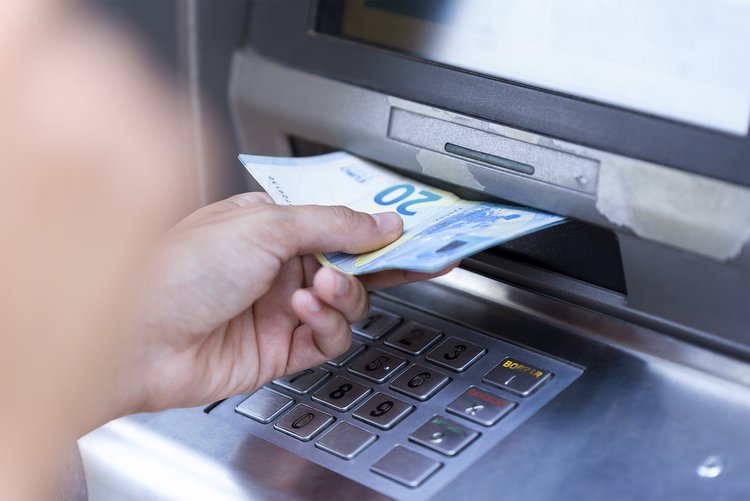 Close up eines Mannes, der 20 Euro Banknoten am Geldautomaten zieht.